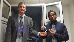 Michael Free (left) holds a light emitting diode and Prashant Sarswat (right) holds carbon dots in suspension. 